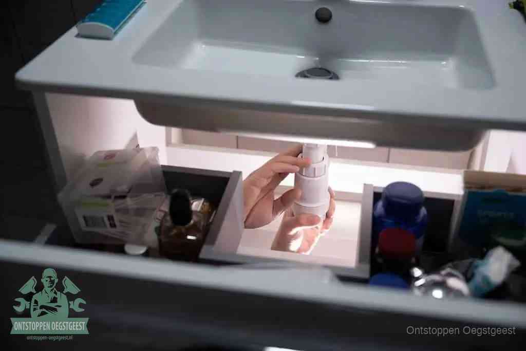 Een pompfles met zeep boven een wastafel, de heet water en afwasmiddel-methode om een vetprop in de afvoer los te maken in Oegstgeest