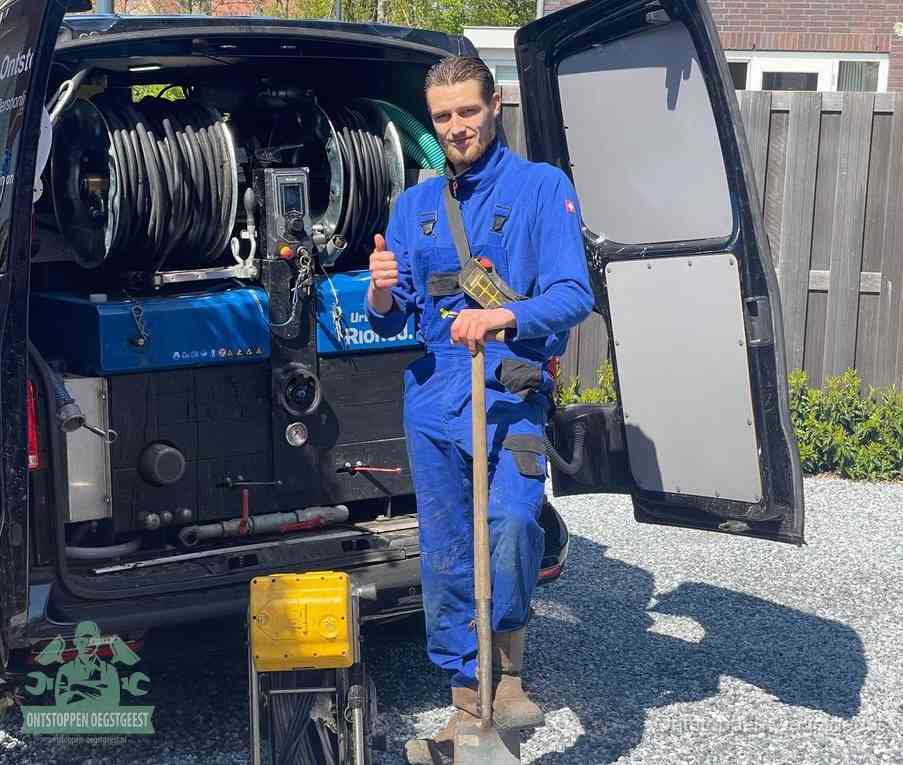 Een monteur bij de werkbus met grote hogedruk-slanghaspels, apparatuur voor hardnekkige afvoerverstoppingen in Oegstgeest
