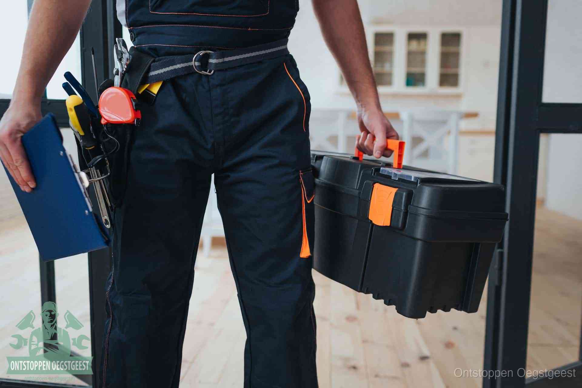 Een monteur met gereedschapsriem en klembord in een keuken, klaar om een transparante prijs voor het gootsteen ontstoppen in Oegstgeest te geven