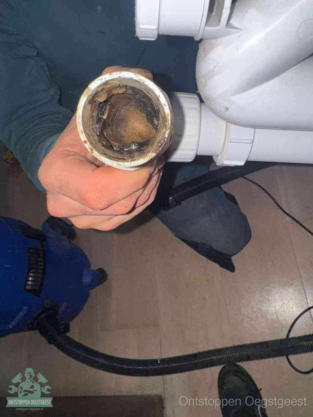 Een losgekoppeld PVC-afvoerbuisstuk dat van binnen volledig is dichtgeslibd met vet en vuil, de meest voorkomende oorzaak van verstoppingen in Oegstgeest