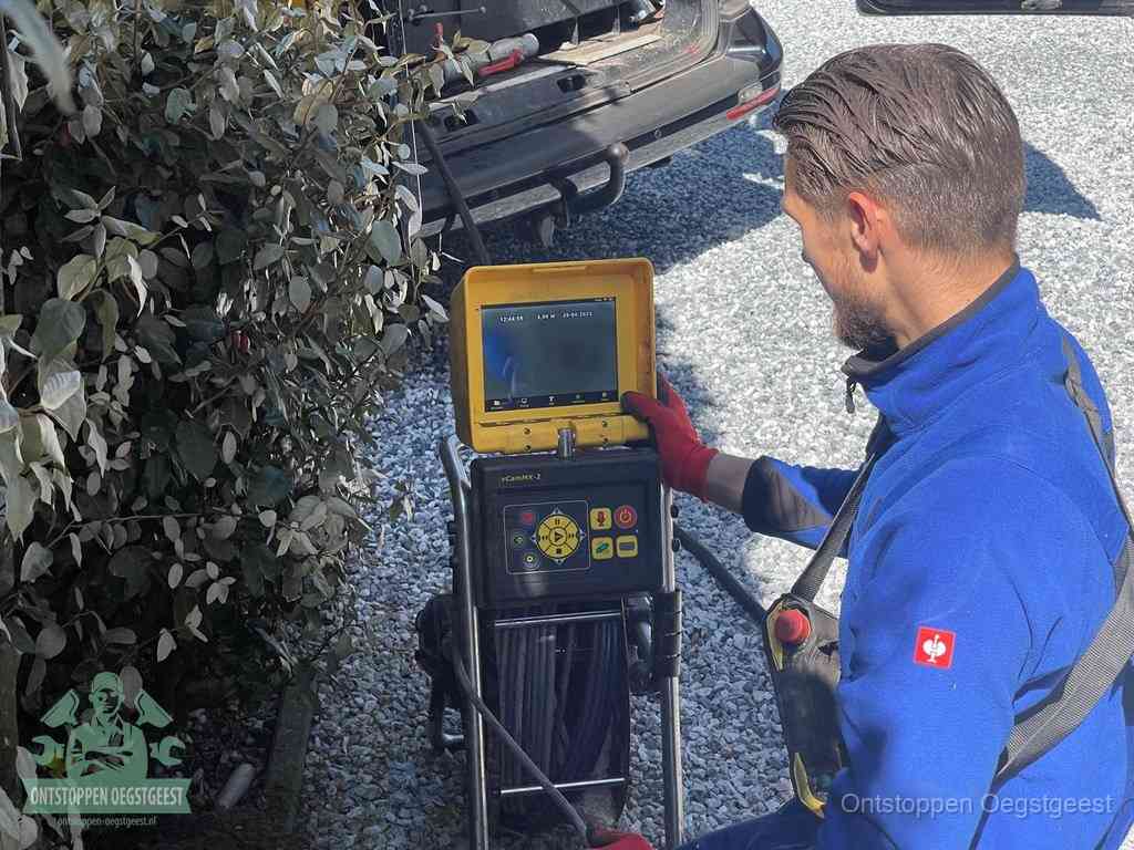 Een monteur bedient een rioolinspectiecamera met monitor en haspel om de verstopping in beeld te brengen in Oegstgeest