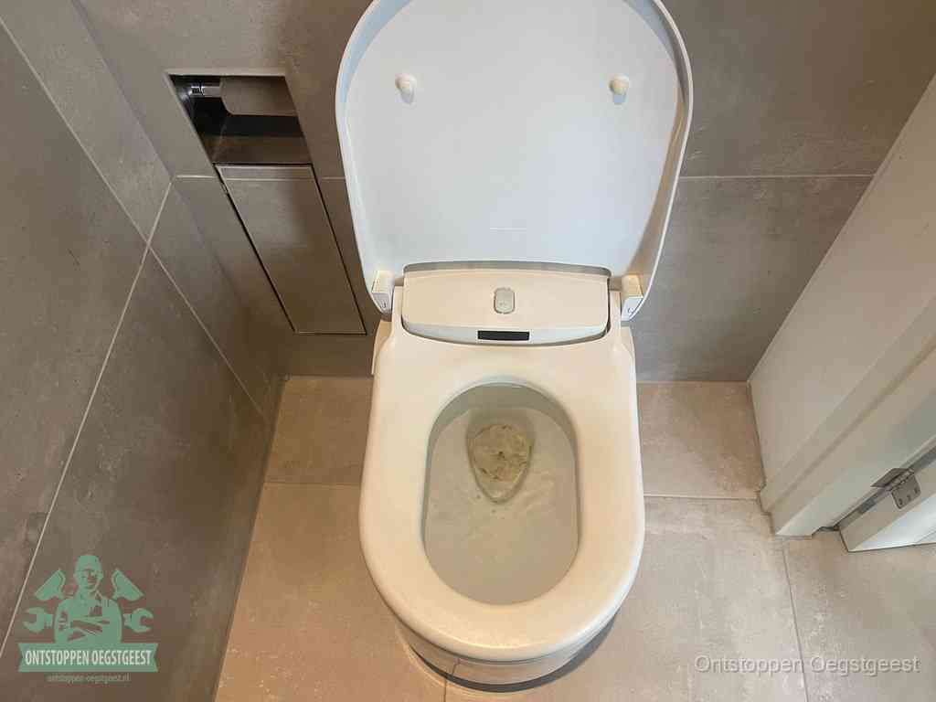 Een wit hangtoilet waarin een prop wc-papier op het water blijft drijven, een duidelijk signaal van een verstopte wc in Oegstgeest