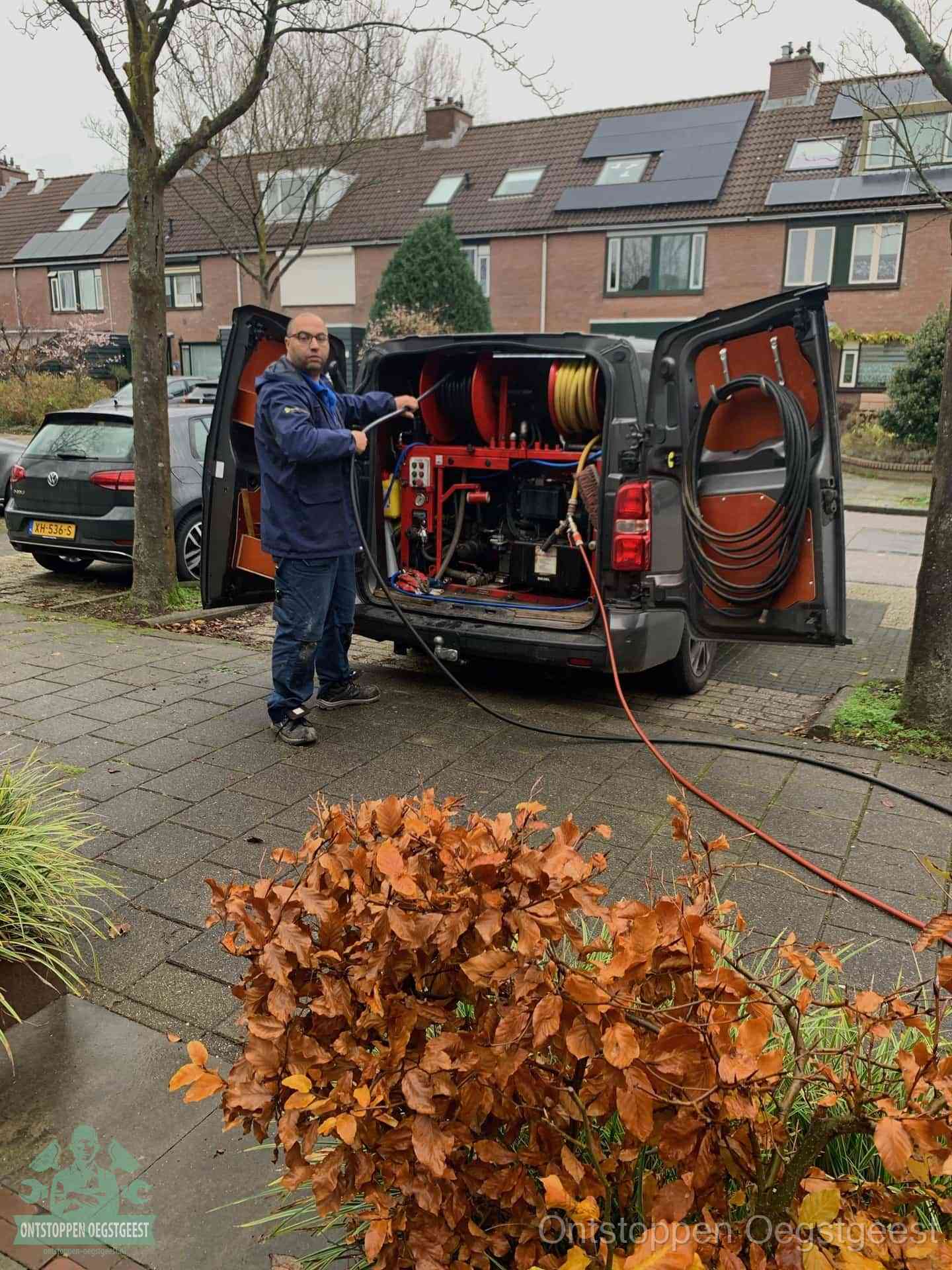 Een monteur staat bij zijn open bestelbus met hogedruk-rioolreinigingsapparatuur, klaar om binnen 30 minuten uit te rukken voor een spoedverstopping in Oegstgeest