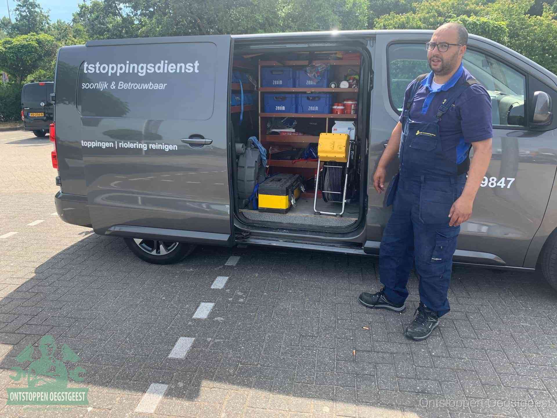 Een monteur staat klaar bij zijn bedrijfsbus met gereedschap, de vaste werkwijze van de ontstoppingsdienst in Oegstgeest